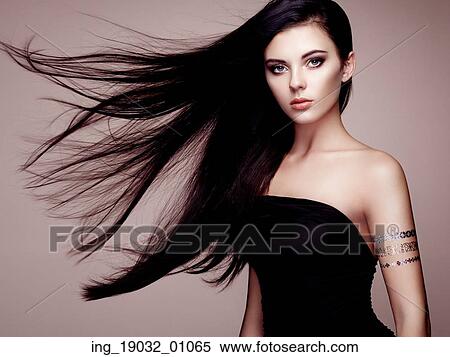 Stock Photography - Fashion portrait of elegant woman with magnificent hair. Brunette girl. Perfect make-up. Girl in elegant dress. Flash tattoo gold. Fotosearch