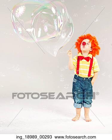 Stock Image - Funny picture of little clown making huge soap bubbles. Fotosearch