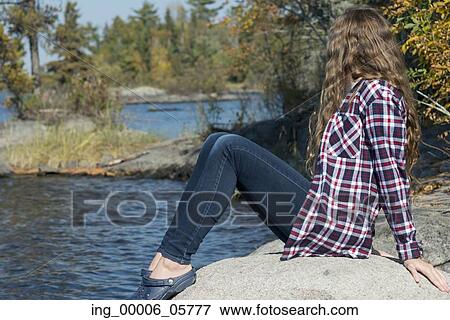 Girl sitting on rock at lakeside, Lake of the Woods, Ontario, Canada View Large Photo Image Stock Photo - Girl sitting on rock at lakeside, Lake of the Woods, Ontario, Canada. Fotosearch