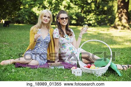 Stock Photography - Glad girlfriends relaxing on the blanket. Fotosearch