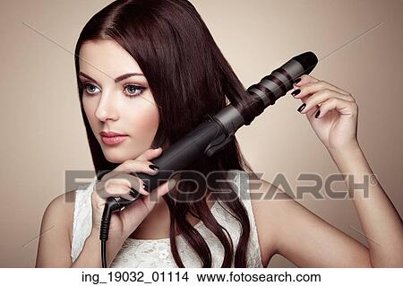 Hairdresser woman curls her hair. Portrait of young beautiful girl with luxurious hair. Fashion and beauty. Perfect make-up View Large Photo Image Picture - Hairdresser woman curls her hair. Portrait of young beautiful girl with luxurious hair. Fashion and beauty. Perfect make-up. Fotosearch