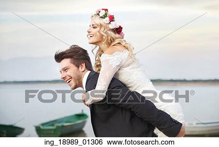 Stock Photograph - Happy husband carrying his lovely wife. Fotosearch