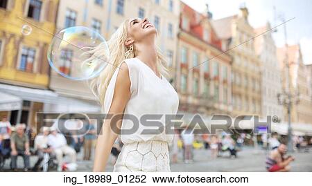 Stock Image - Joyful woman among the soap bubbles. Fotosearch