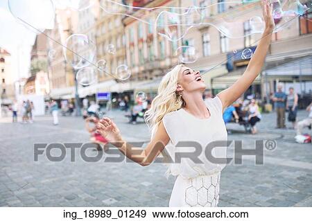 Stock Photo - Joyful woman playing the soap bubbles. Fotosearch