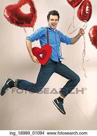 Picture - Laughing and jumping guy with valentine&rsquo; s balloons. Fotosearch