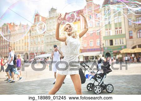 Stock Photography - Laughing blond woman making soap bubbles. Fotosearch