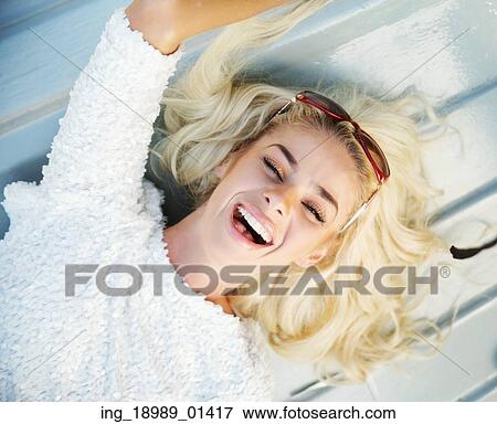 Stock Photo - Laughing lady lying on the wooden floor. Fotosearch