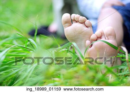 Stock Photo - Little boy&rsquo; s feet on fresh grass. Fotosearch
