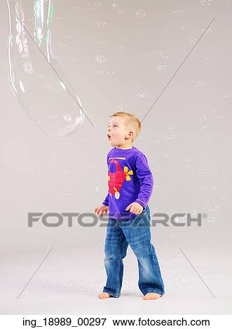 Stock Photo - Little cute kid playing a soap bubbles. Fotosearch