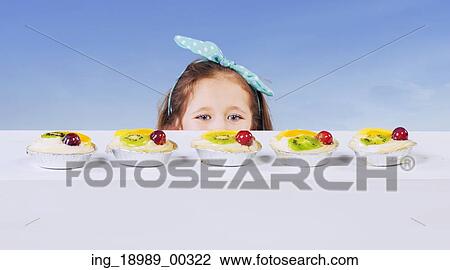 Stock Image - Little girl and the delicious fruit cake. Fotosearch