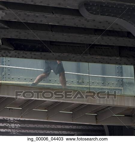 Stock Image - Low section view of a man walking on footbridge, Chelsea, Manhattan, New York City, New York State, USA. Fotosearch