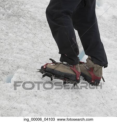 Stock Image - Low section view of man hiking in snow, Perito Moreno Glacier, Los Glaciares National Park, Santa Cruz Province, Patagonia, Argentina. Fotosearch