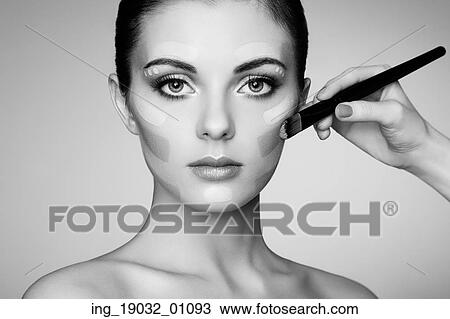 Stock Image - Makeup artist applies skintone. Beautiful woman face. Perfect makeup. Skincare foundation. Black and white. Fotosearch