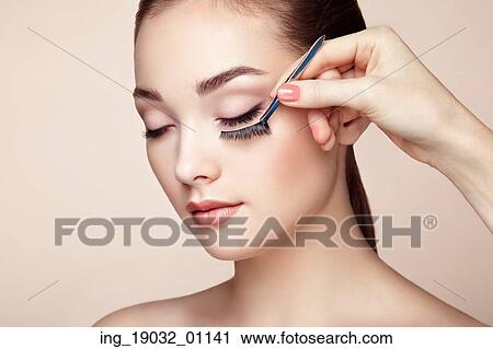Stock Image - Makeup artist glues eyelashes. Beautiful woman face. Perfect makeup. Beauty fashion. Eyelashes. Cosmetic Eyeshadow. Fotosearch
