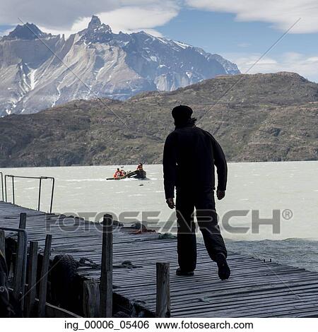 Stock Photograph - Man walking on jetty at Grey Lake, Torres del Paine National Park, Patagonia, Chile. Fotosearch