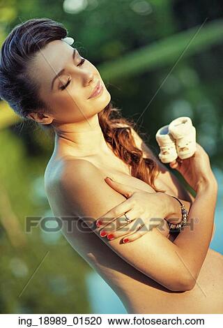Stock Image - Mom holding little shoes of her child. Fotosearch