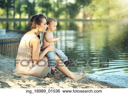 Stock Photograph - Mom with son looking at the calm lake. Fotosearch