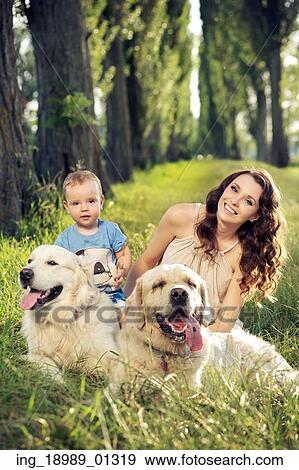Stock Photo - Mother and baby playing with dogs. Fotosearch