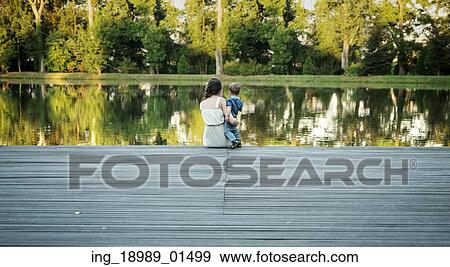 Stock Photo - Mother carrying her baby and looking at the lake. Fotosearch