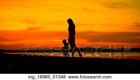 Stock Photo - Mother with child looking at the beautiful sunset. Fotosearch
