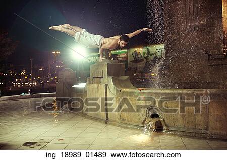 Stock Photo - Muscular guy doing push-ups in a fountain. Fotosearch