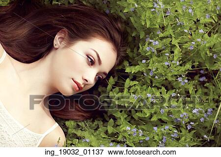 Stock Photo - Portrait of a beautiful young woman in summer garden. Girl on nature. Spring flowers. Fashion beauty. Fotosearch