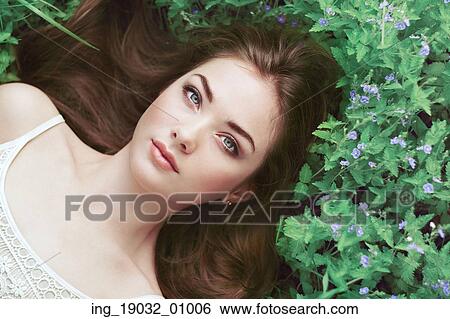 Stock Photograph - Portrait of a beautiful young woman in summer garden. Girl on nature. Spring flowers. Fashion beauty. Fotosearch