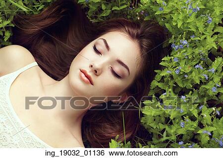 Stock Photograph - Portrait of a beautiful young woman in summer garden. Girl on nature. Spring flowers. Fashion beauty. Fotosearch