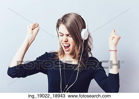 Stock Image - portrait of a young woman listening to music with headphones. Fotosearch