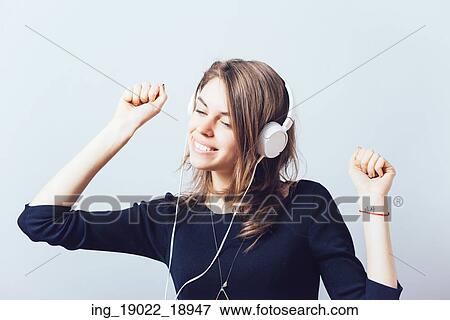 Stock Photo - portrait of a young woman listening to music with headphones. Fotosearch
