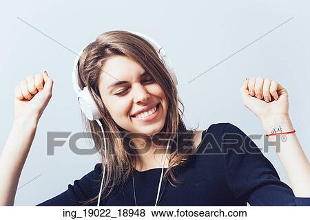 Stock Photo - portrait of a young woman listening to music with headphones. Fotosearch