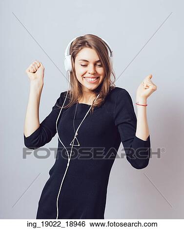 Stock Photograph - portrait of a young woman listening to music with headphones. Fotosearch