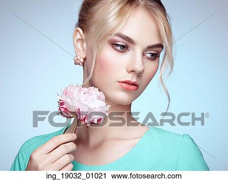 Stock Image - Portrait of beautiful sensual woman with elegant hairstyle. Perfect makeup. Blonde girl. Fashion photo. Flowers. Fotosearch