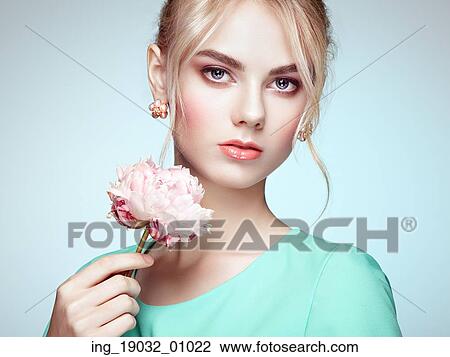 Stock Image - Portrait of beautiful sensual woman with elegant hairstyle. Perfect makeup. Blonde girl. Fashion photo. Flowers. Fotosearch