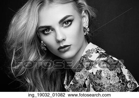 Stock Image - Portrait of beautiful sensual woman with elegant hairstyle. Perfect makeup. Blonde girl. Fashion photo. Jewelry and dress. Black and white. Fotosearch