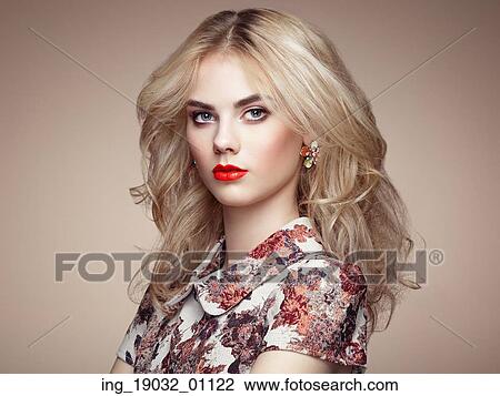 Stock Image - Portrait of beautiful sensual woman with elegant hairstyle. Perfect makeup. Blonde girl. Fashion photo. Jewelry and dress. Fotosearch