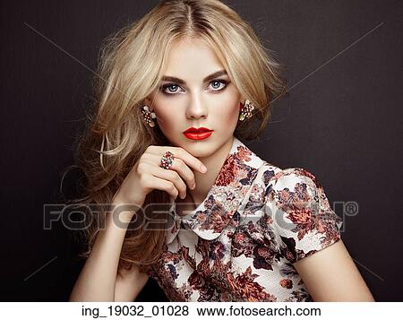 Stock Photo - Portrait of beautiful sensual woman with elegant hairstyle. Perfect makeup. Blonde girl. Fashion photo. Jewelry and dress. Fotosearch