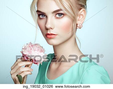 Stock Photograph - Portrait of beautiful sensual woman with elegant hairstyle. Perfect makeup. Blonde girl. Fashion photo. Flowers. Fotosearch