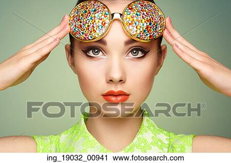 Stock Image - Portrait of beautiful young woman with colored glasses. Beauty fashion. Perfect make-up. Colorful decoration. Jewelry. Fotosearch