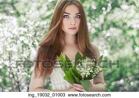 Portrait of beautiful young woman with lily of the valley. Girl on nature. Spring flowers. Fashion beauty View Large Photo Image Stock Image - Portrait of beautiful young woman with lily of the valley. Girl on nature. Spring flowers. Fashion beauty. Fotosearch