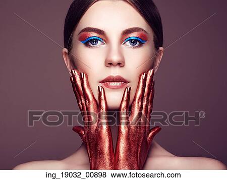 Portrait of beautiful young woman with art make-up. Bronze hand. Beauty fashion View Large Photo Image Stock Photo - Portrait of beautiful young woman with art make-up. Bronze hand. Beauty fashion. Fotosearch