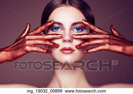 Stock Photo - Portrait of beautiful young woman with art make-up. Bronze hand. Beauty fashion. Fotosearch