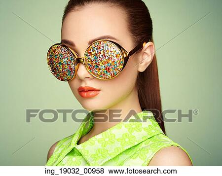 Stock Photo - Portrait of beautiful young woman with colored glasses. Beauty fashion. Perfect make-up. Colorful decoration. Jewelry. Fotosearch