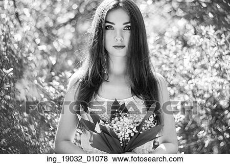 Stock Photo - Portrait of beautiful young woman with lily of the valley. Girl on nature. Spring flowers. Fashion beauty. Black and white. Fotosearch