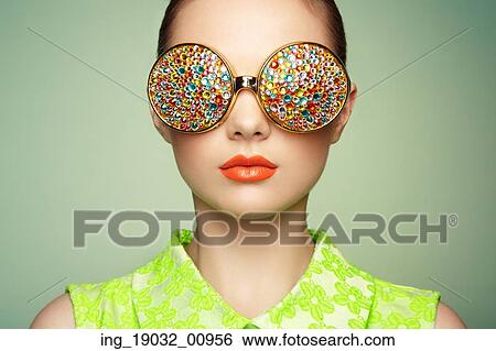 Stock Photograph - Portrait of beautiful young woman with colored glasses. Beauty fashion. Perfect make-up. Colorful decoration. Jewelry. Fotosearch