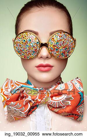 Stock Photography - Portrait of beautiful young woman with colored glasses. Beauty fashion. Perfect make-up. Colorful decoration. Jewelry. Fotosearch