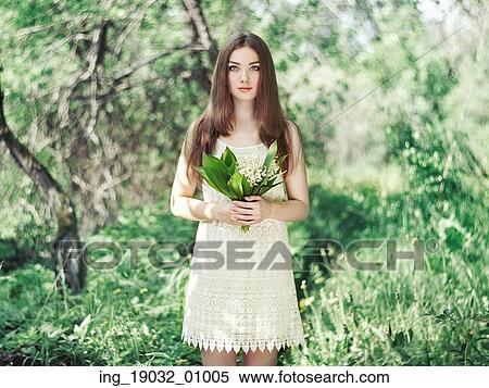 Stock Photography - Portrait of beautiful young woman with lily of the valley. Girl on nature. Spring flowers. Fashion beauty. Fotosearch