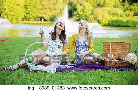 Stock Image - Portrait of the laughing women sitting on the deep purple blanket. Fotosearch