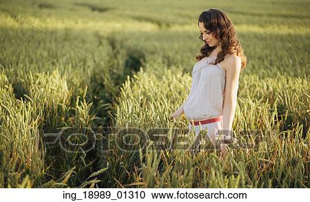 Stock Image - Portrait of the woman on the fresh cereal field. Fotosearch