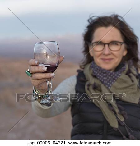 Portrait of woman holding a wine glass in desert, San Pedro de Atacama, El Loa Province, Antofagasta Region, Chile View Large Photo Image Stock Image - Portrait of woman holding a wine glass in desert, San Pedro de Atacama, El Loa Province, Antofagasta Region, Chile. Fotosearch